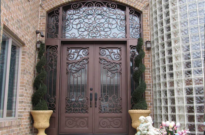Wood and iron double doors with scroll grilles under an arched iron transom