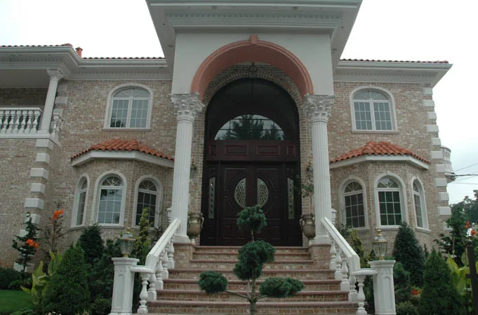 Arched wood double doors under a tall columned portico with curved white stair railings