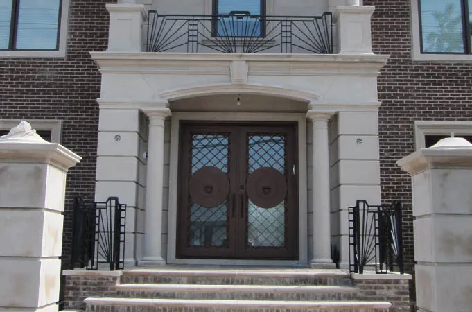 Wood double doors with diamond-pattern glass in a stone portico