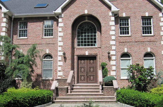 Brick house with carved wood double doors at the top of brick steps