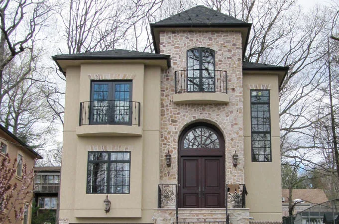 Stucco and stone house with wood double doors under an arched transom