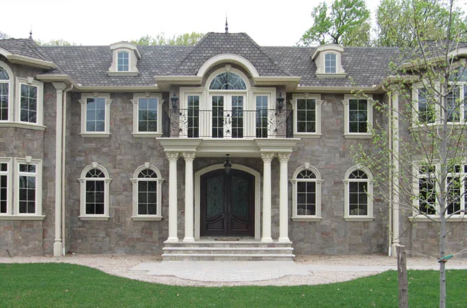 Stone house with arched double doors under a columned balcony