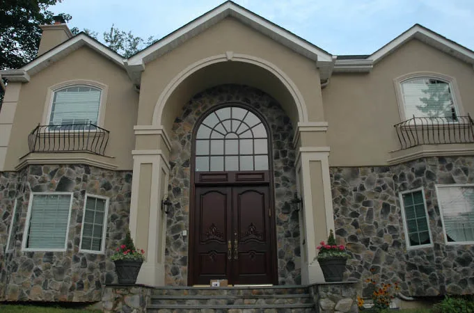 Arched wood double doors with a fan transom in a stone and stucco entry