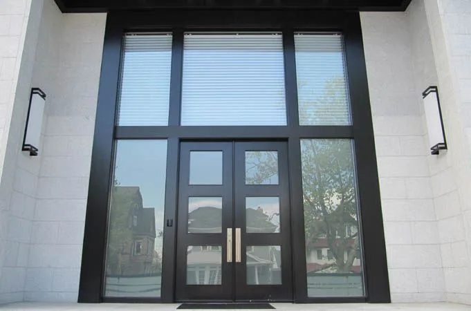 Black-framed glass double doors under a tall glass window wall